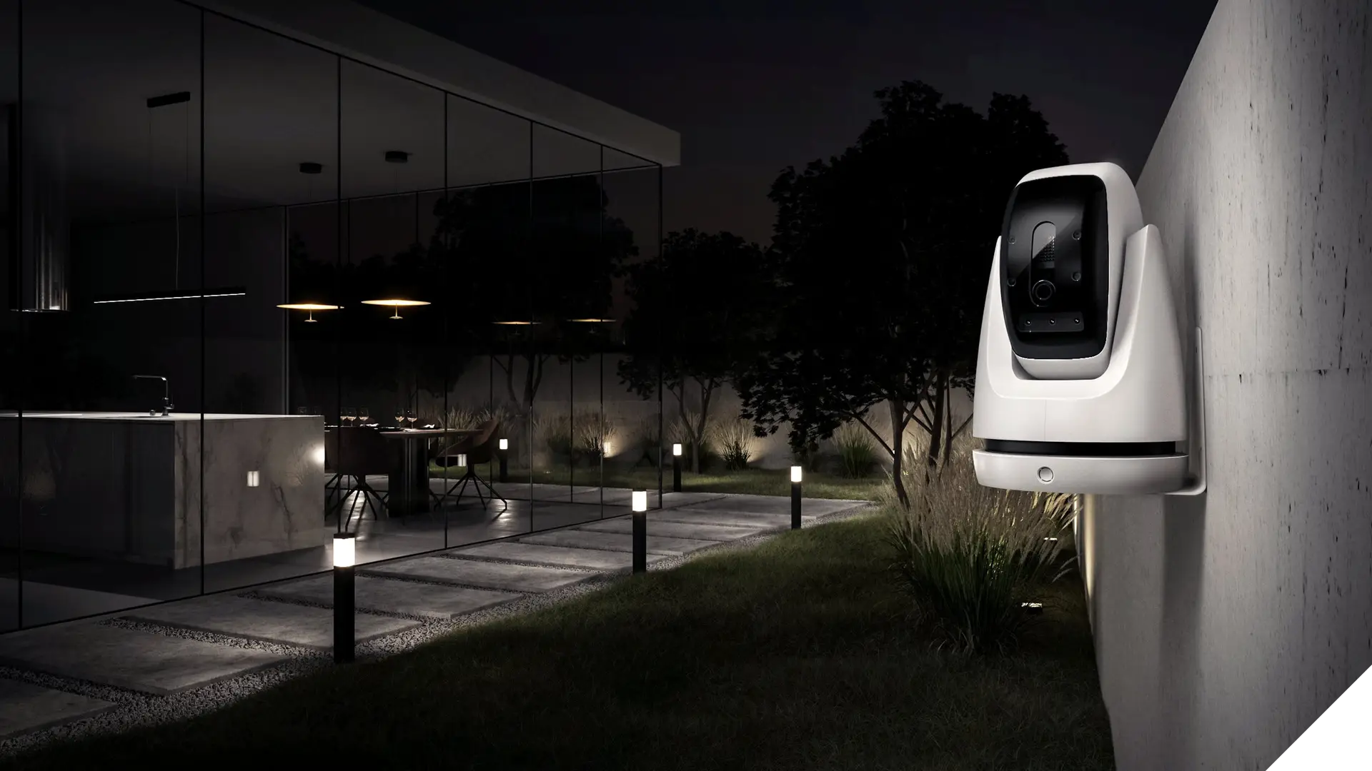 PaintCam varnostna kamera pripeta na betonski zid na osvetljenem vrtu hiše, ki ima steklene stene