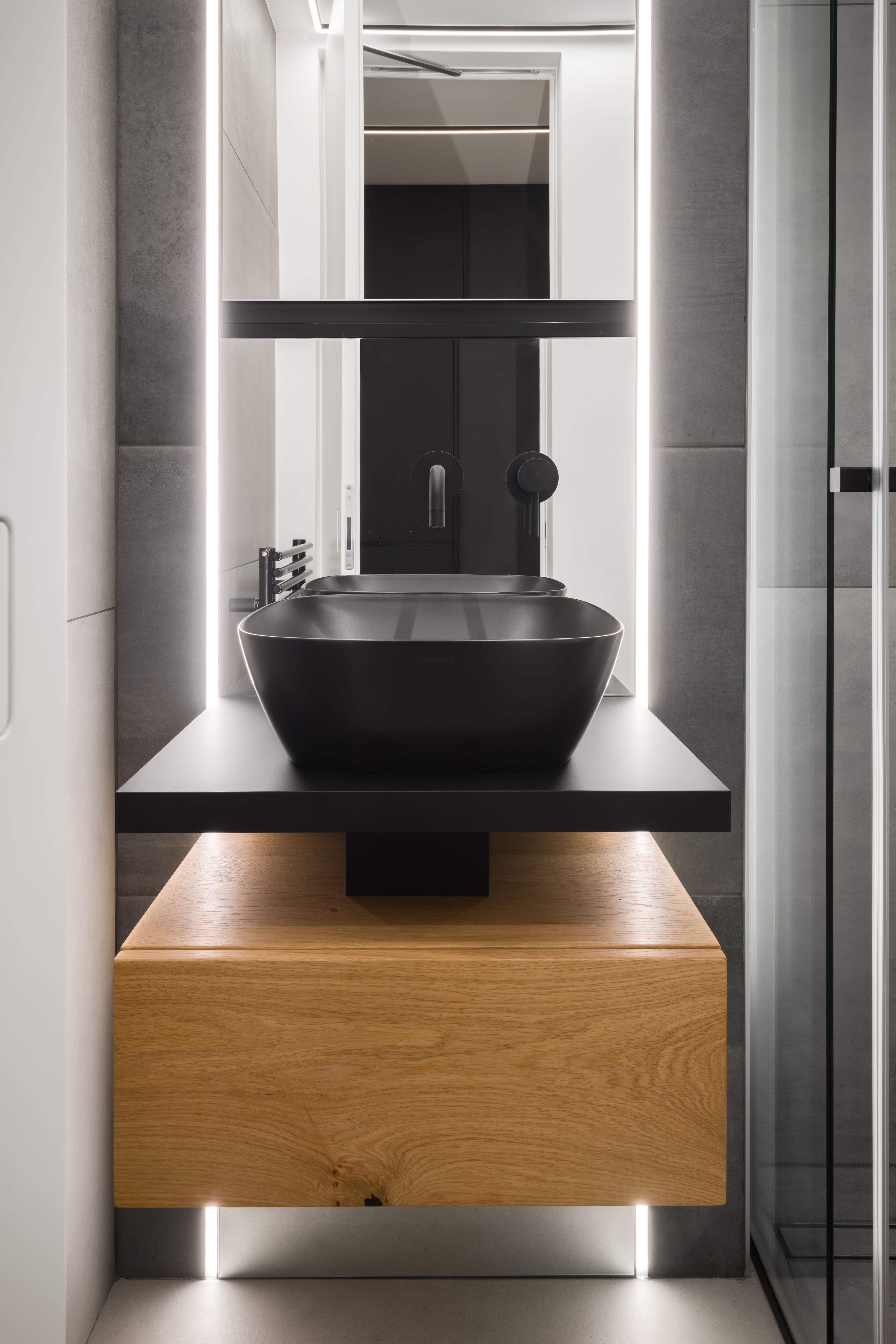 Minimalist bathroom with a black sink and a wooden drawer