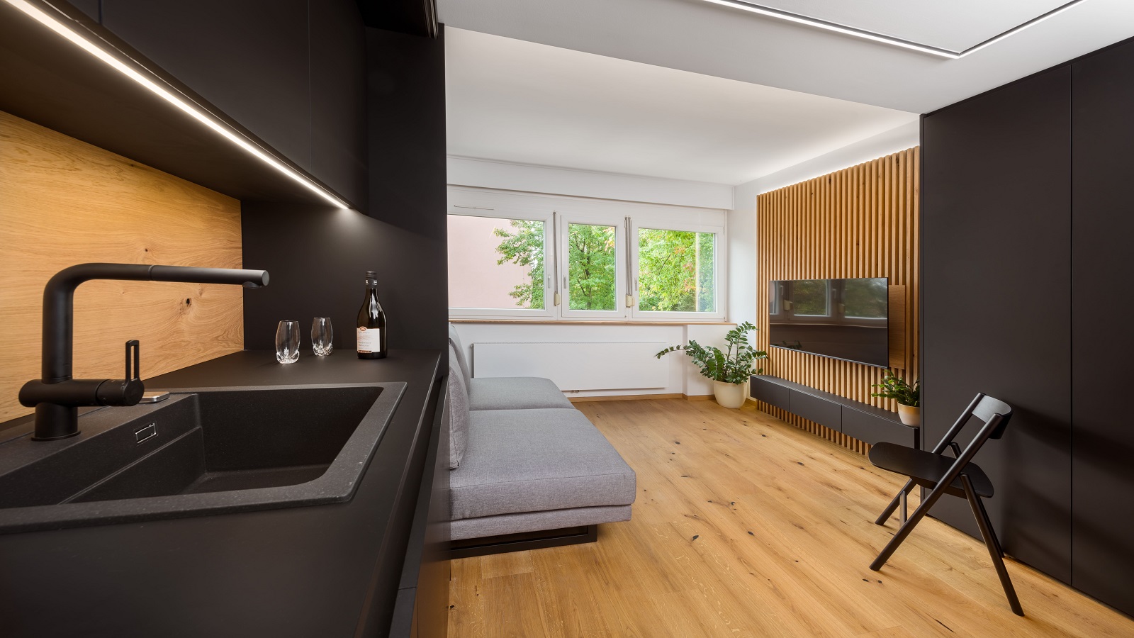 Kitchen with black countertop that flows into the living area with natural light
