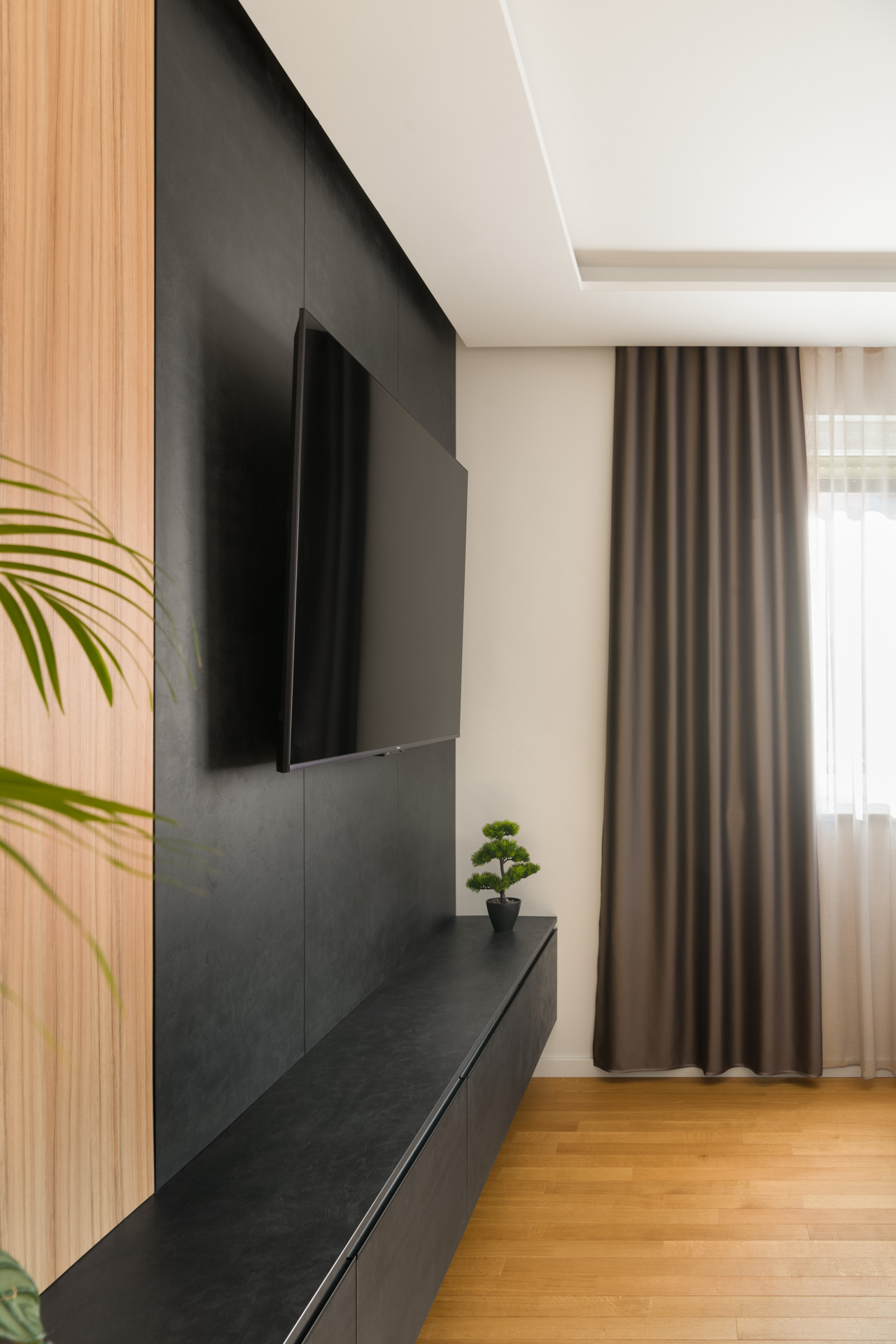 Minimalistična dnevna soba s stensko nameščenim televizorjem in lesenimi detajli