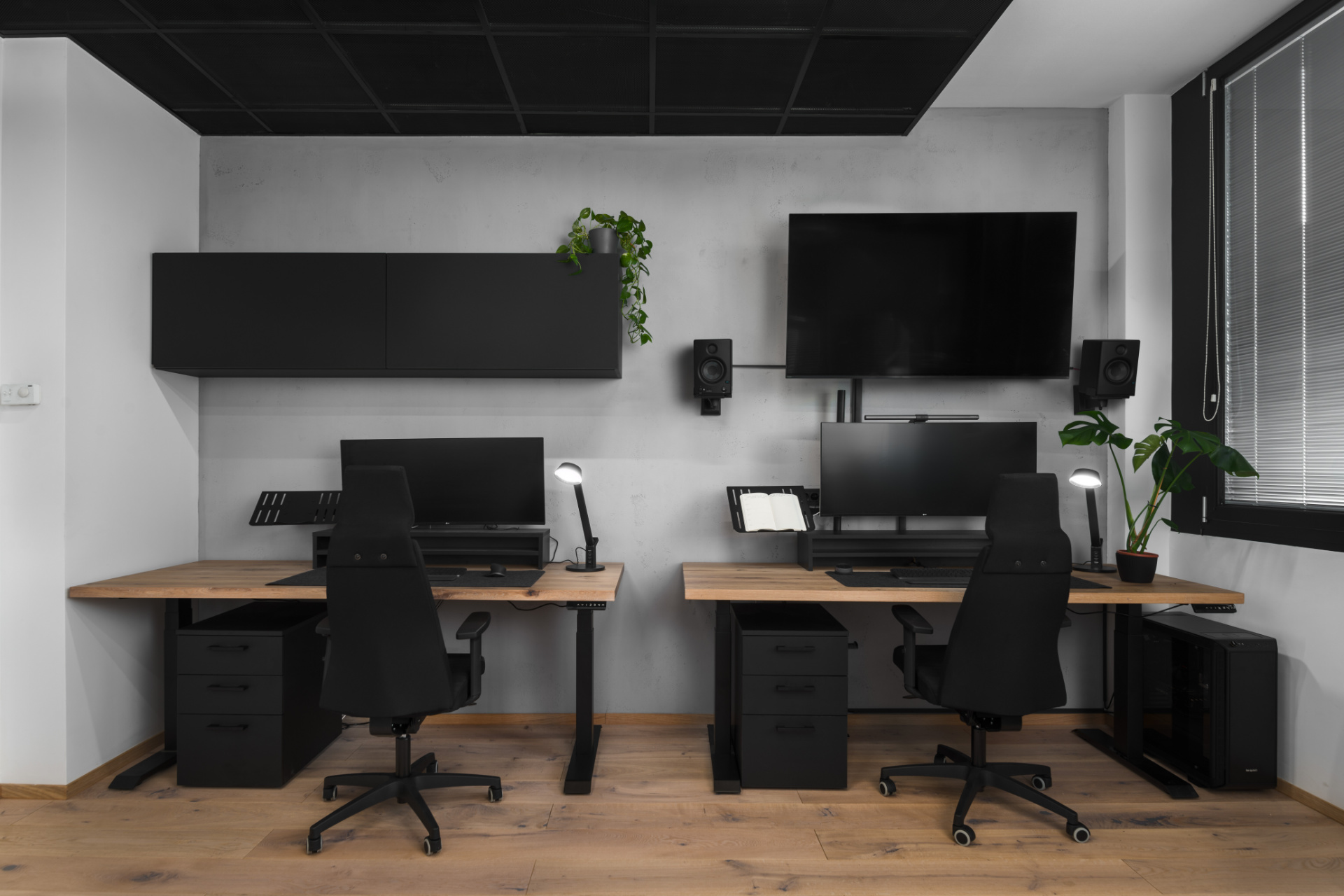 Moderen delovni prostor z dvema pisalnima mizama in črnim pohištvom, delo notranjega oblikovalca