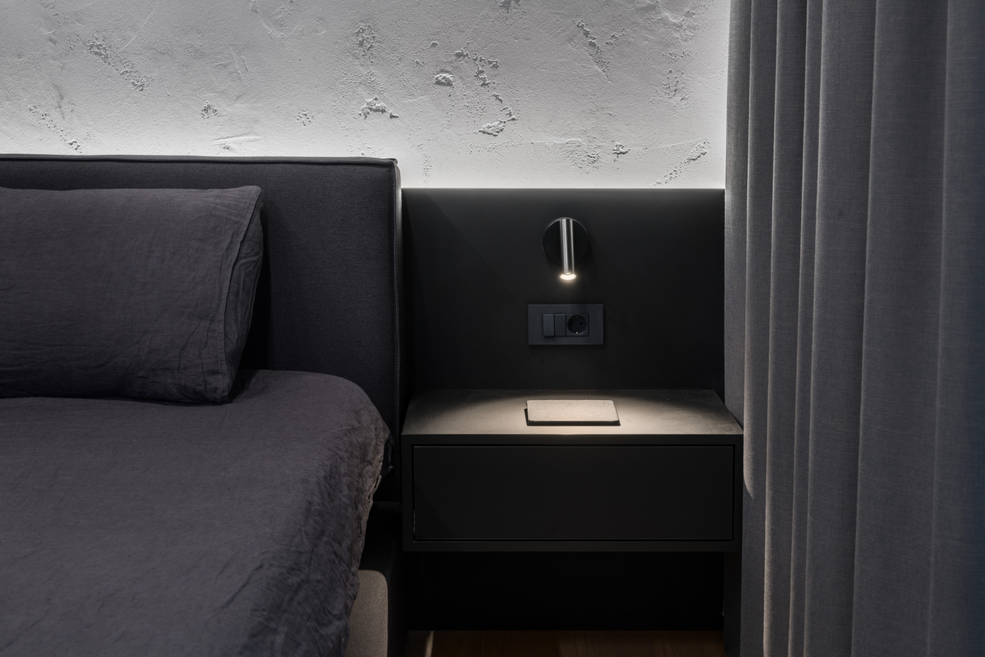Black bedside table with bedside lamp presented as work of an interior designer