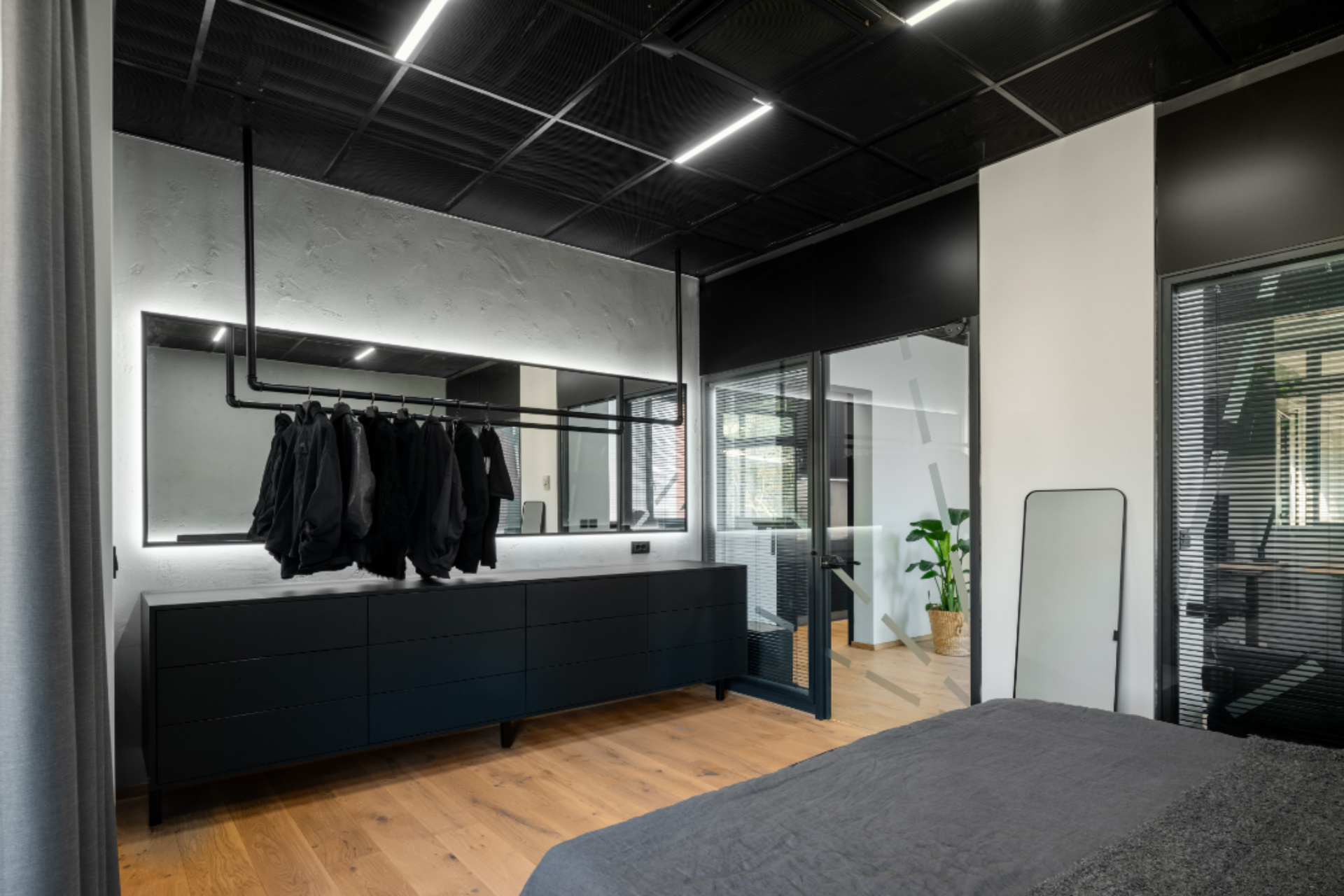 Notranji dizajn garderobe v spalnici s kovinskimi obešalniki in ogledalom