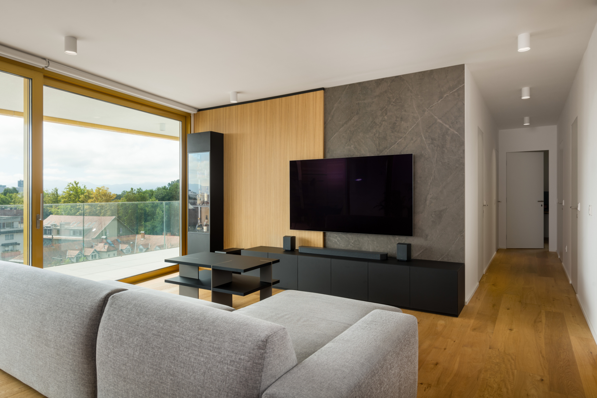 Living room with a sofa, a coffee table, a wall-mounted TV, and a view of the city