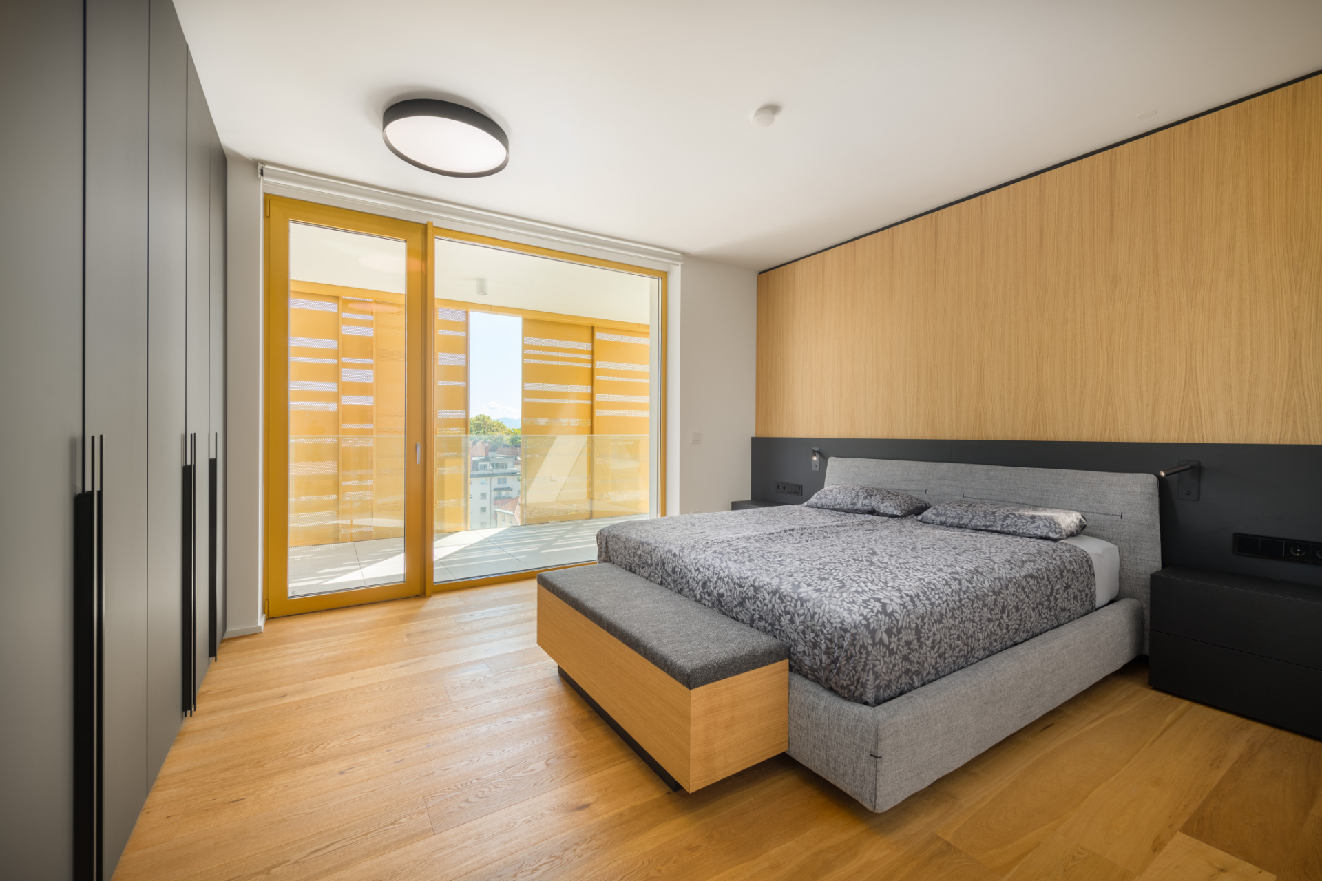 Wooden bedroom with a balcony and black cabinets