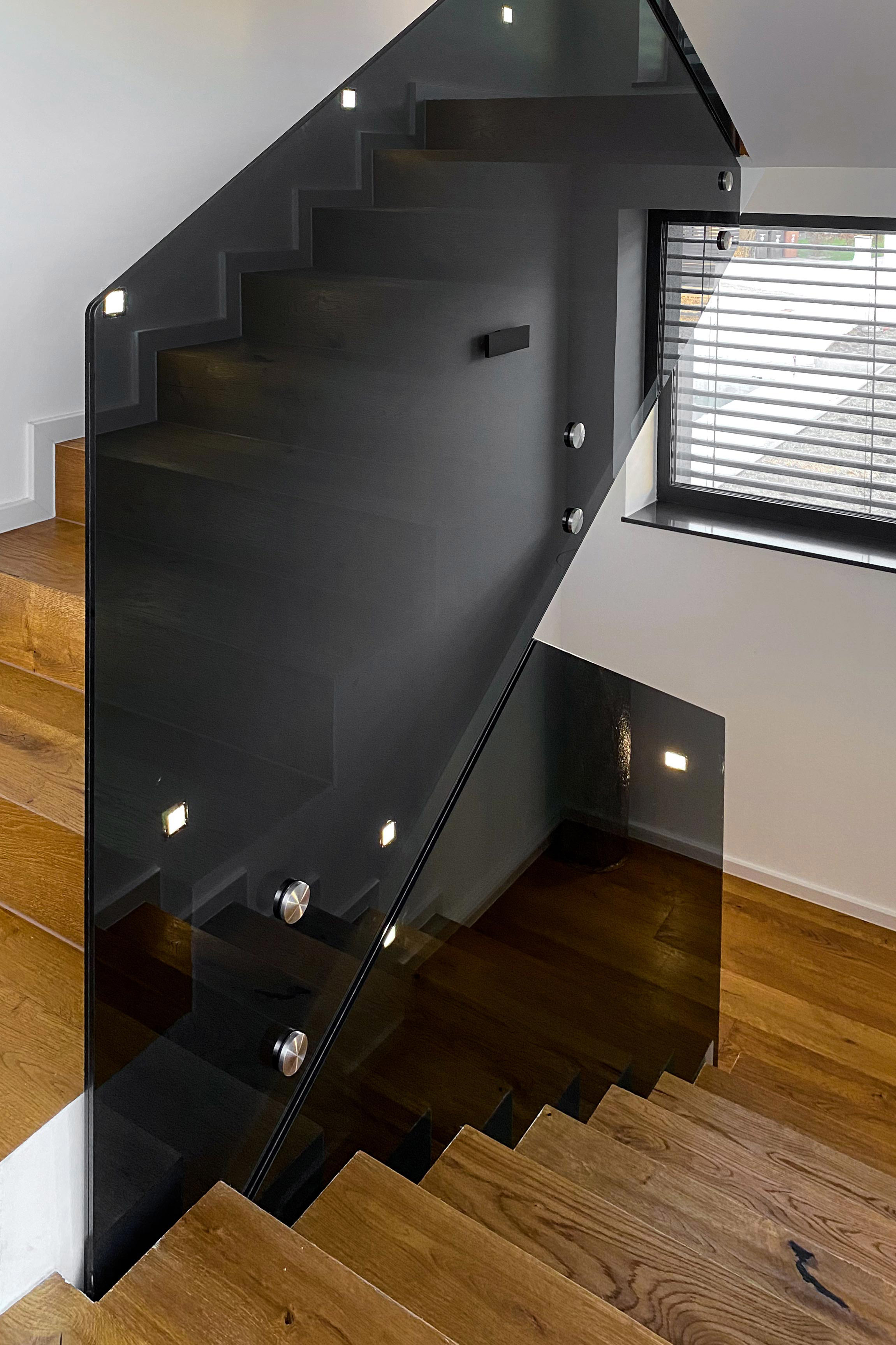 Leseno stopnišče s črno stekleno ograjo, primer modernega dizajna interierja