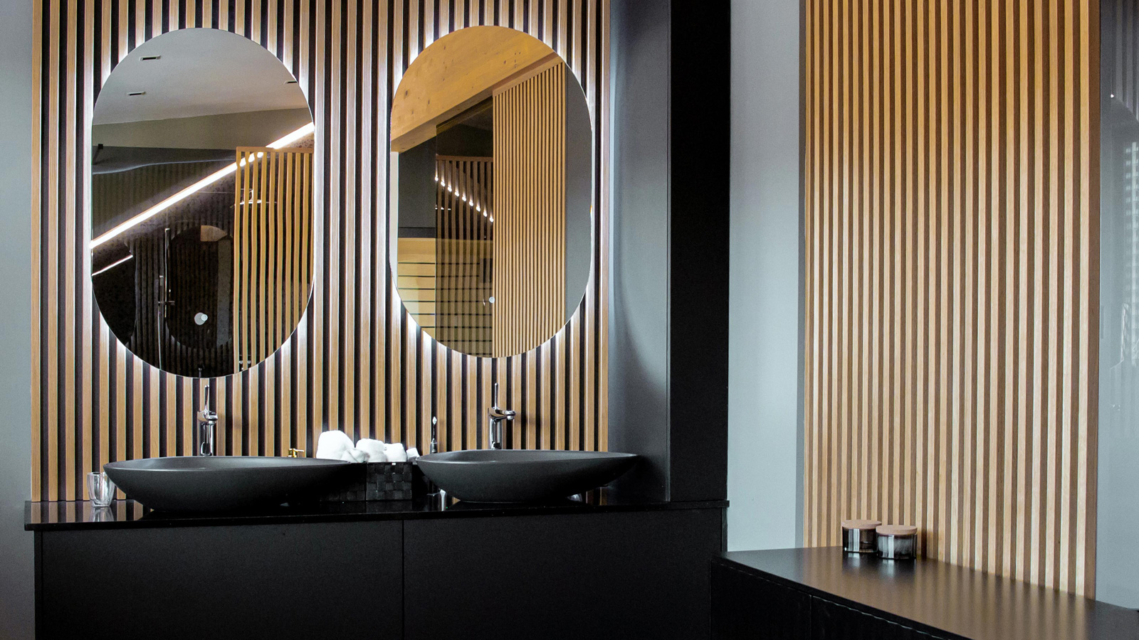 Minimalističen dvojni umivalnik z ogledali v sodobni leseni kopalnici s črnimi detajli