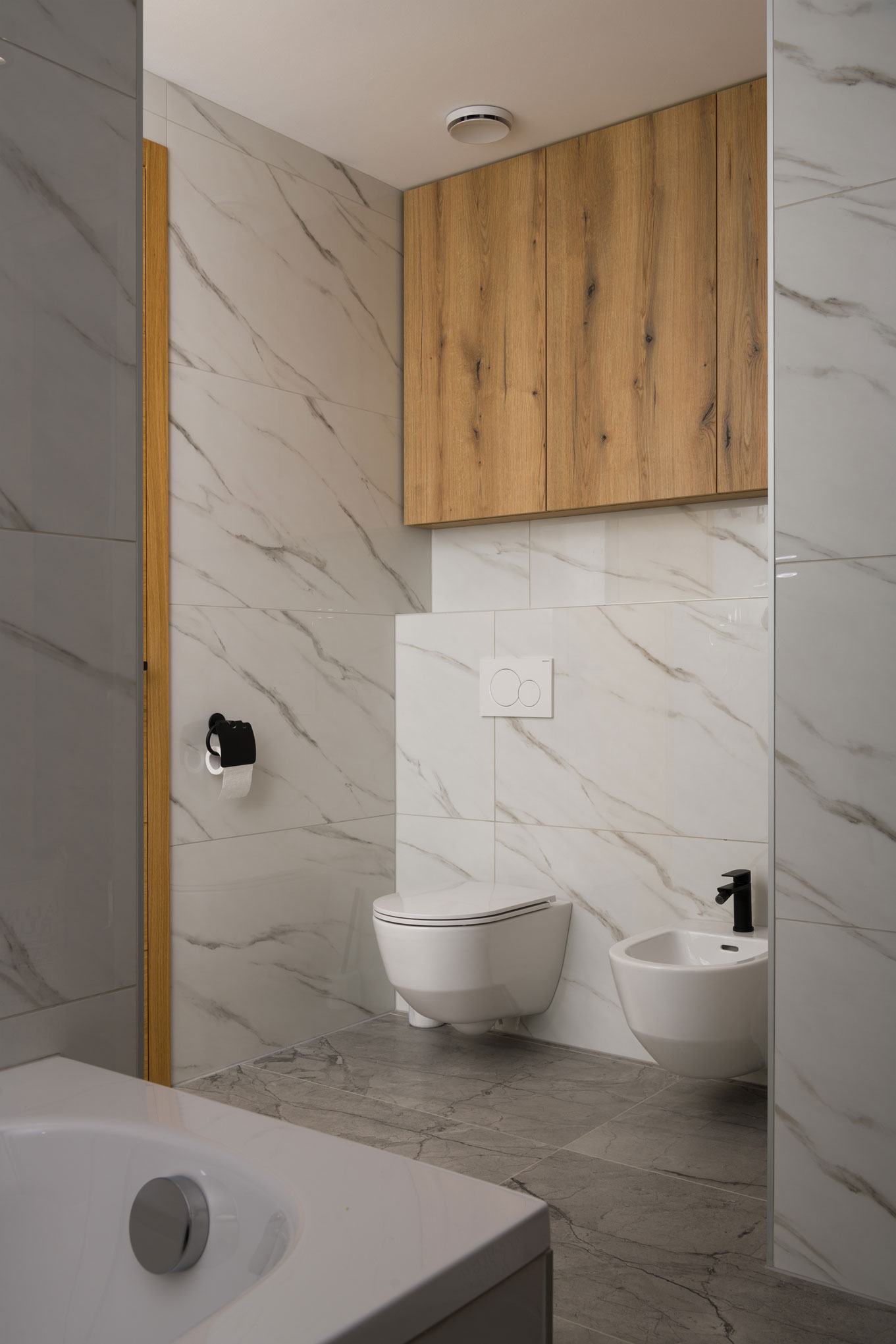 A bathroom with a bathtub and a combination of wooden cabinets and marble tiles in a modern interior