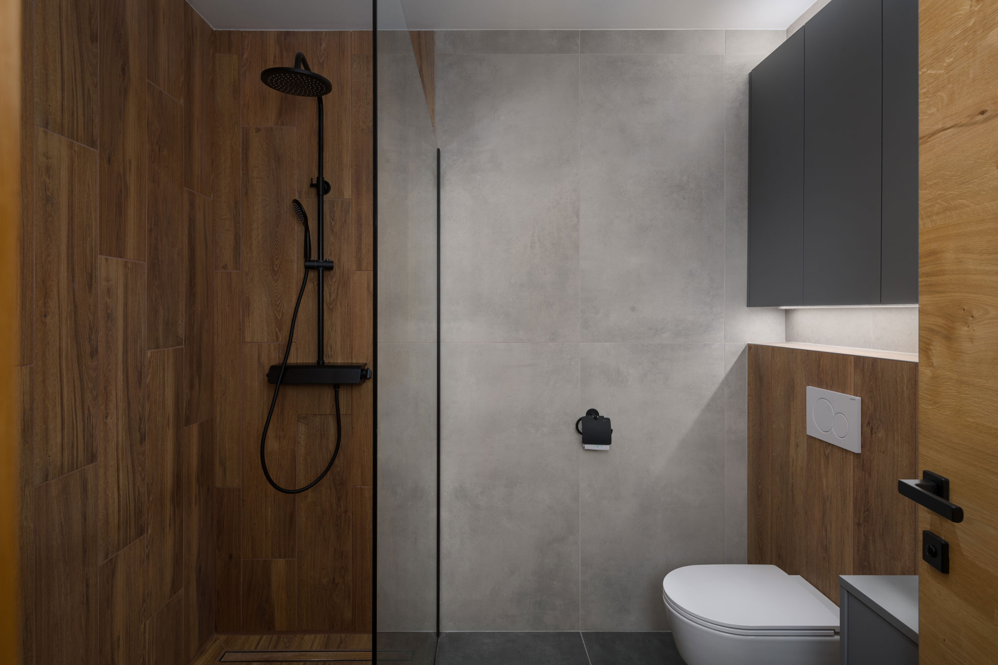 Bathroom with shower cabin and wooden and gray walls, an example of minimalist interior design