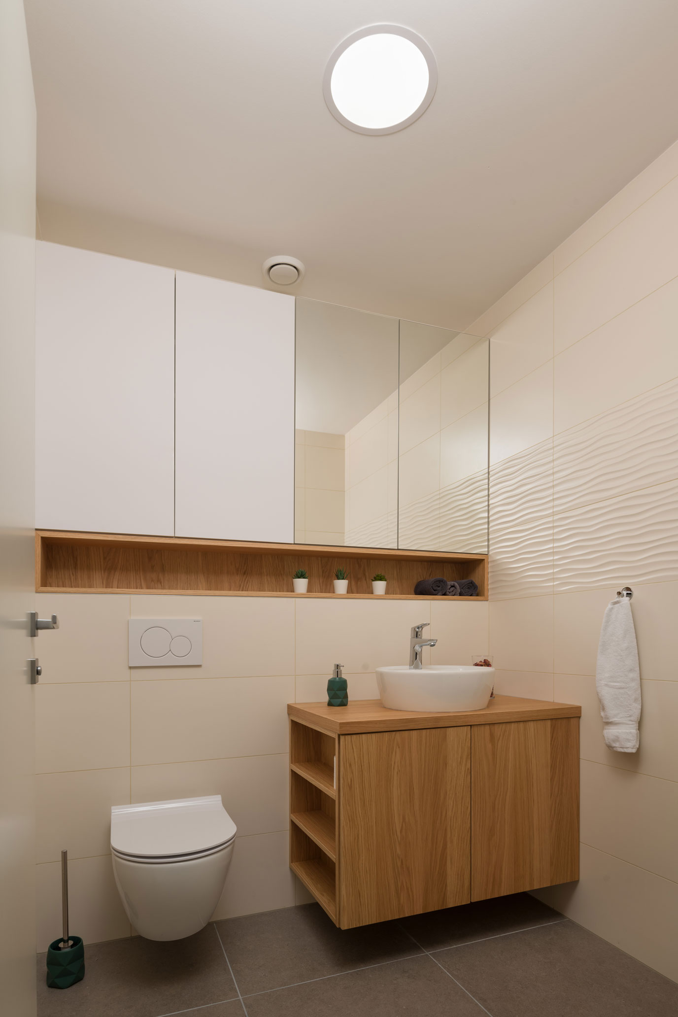 Kopalnica s keramičnimi ploščicami, ogledalom in leseno omaro, primer notranjega oblikovanja prostorov