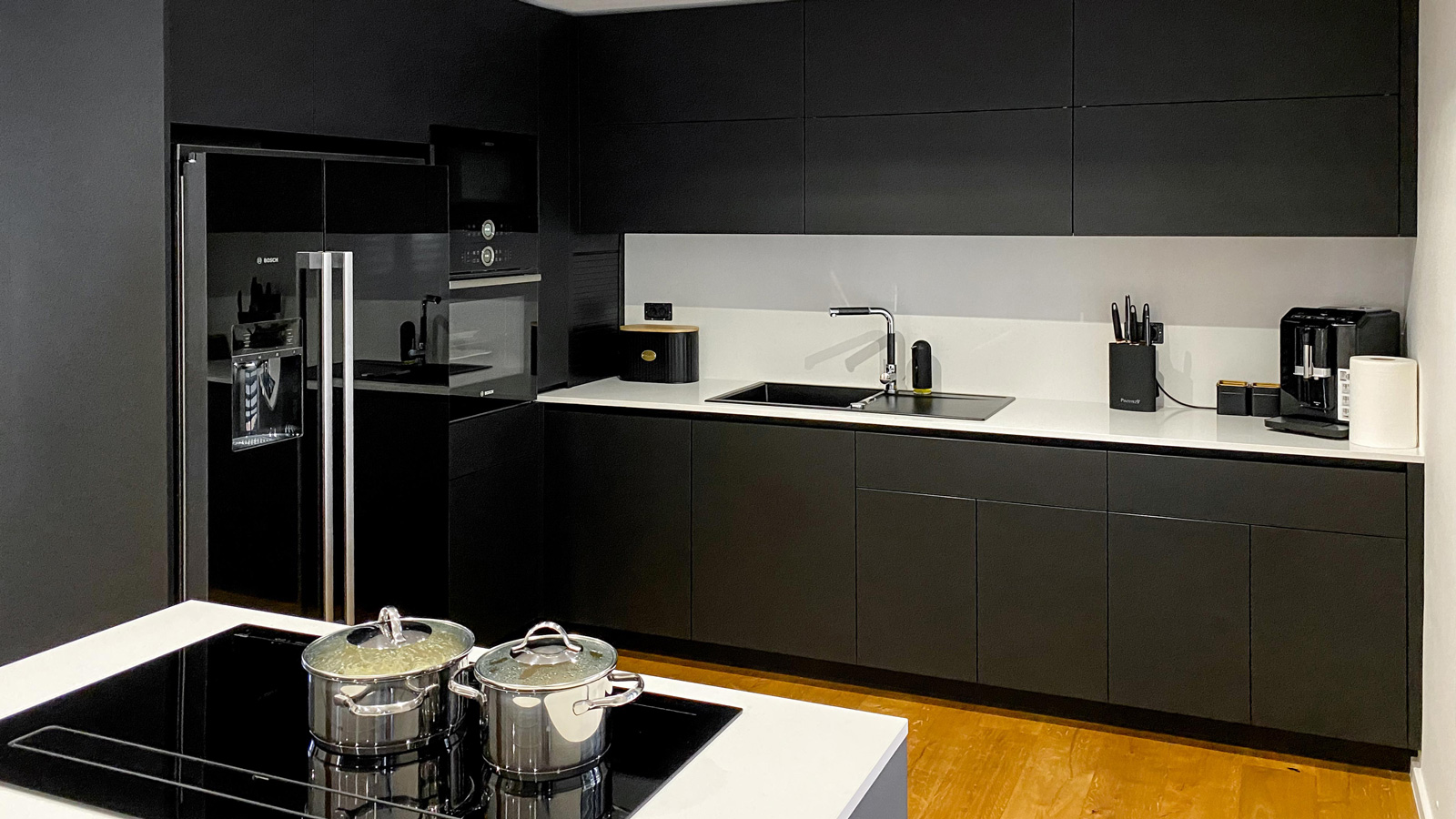 Kuhinja v črni barvi s kuhinjskim otokom in črnimi omarami