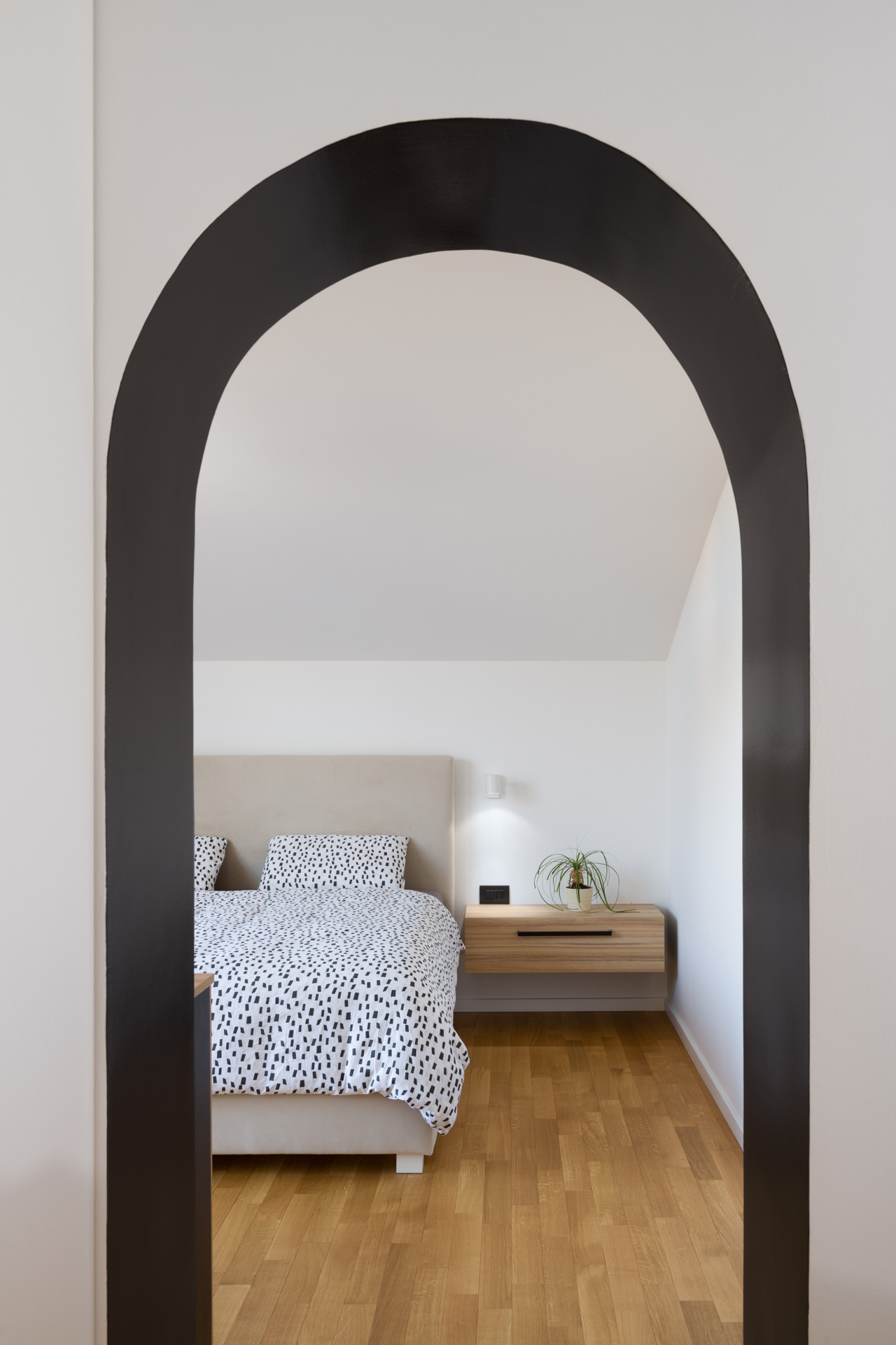 Minimalistična spalnica s svetlimi barvami, nočno omarico in ogledalom