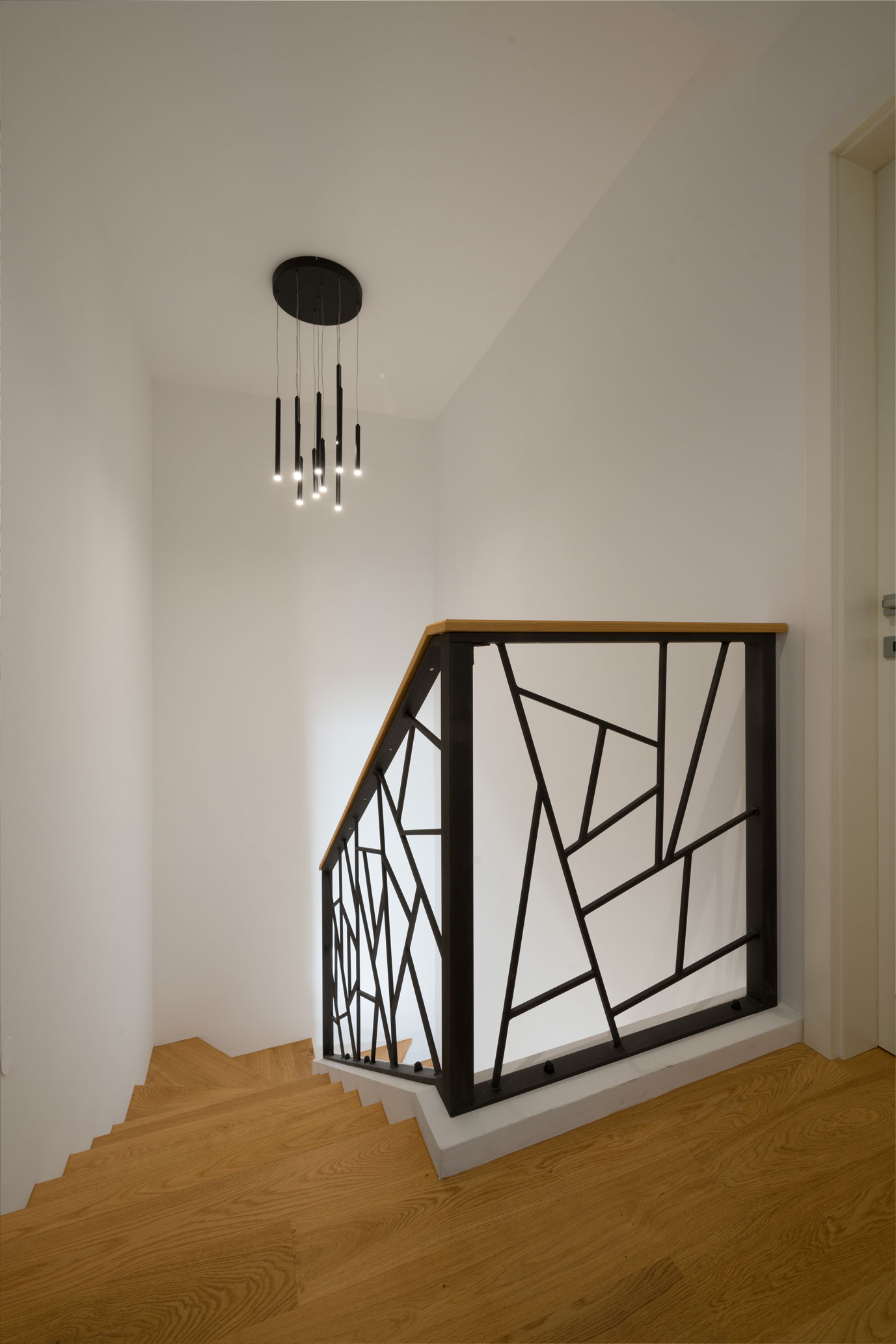 Zavito leseno stopnišče s kovinsko ograjo v minimalistično oblikovanem interierju