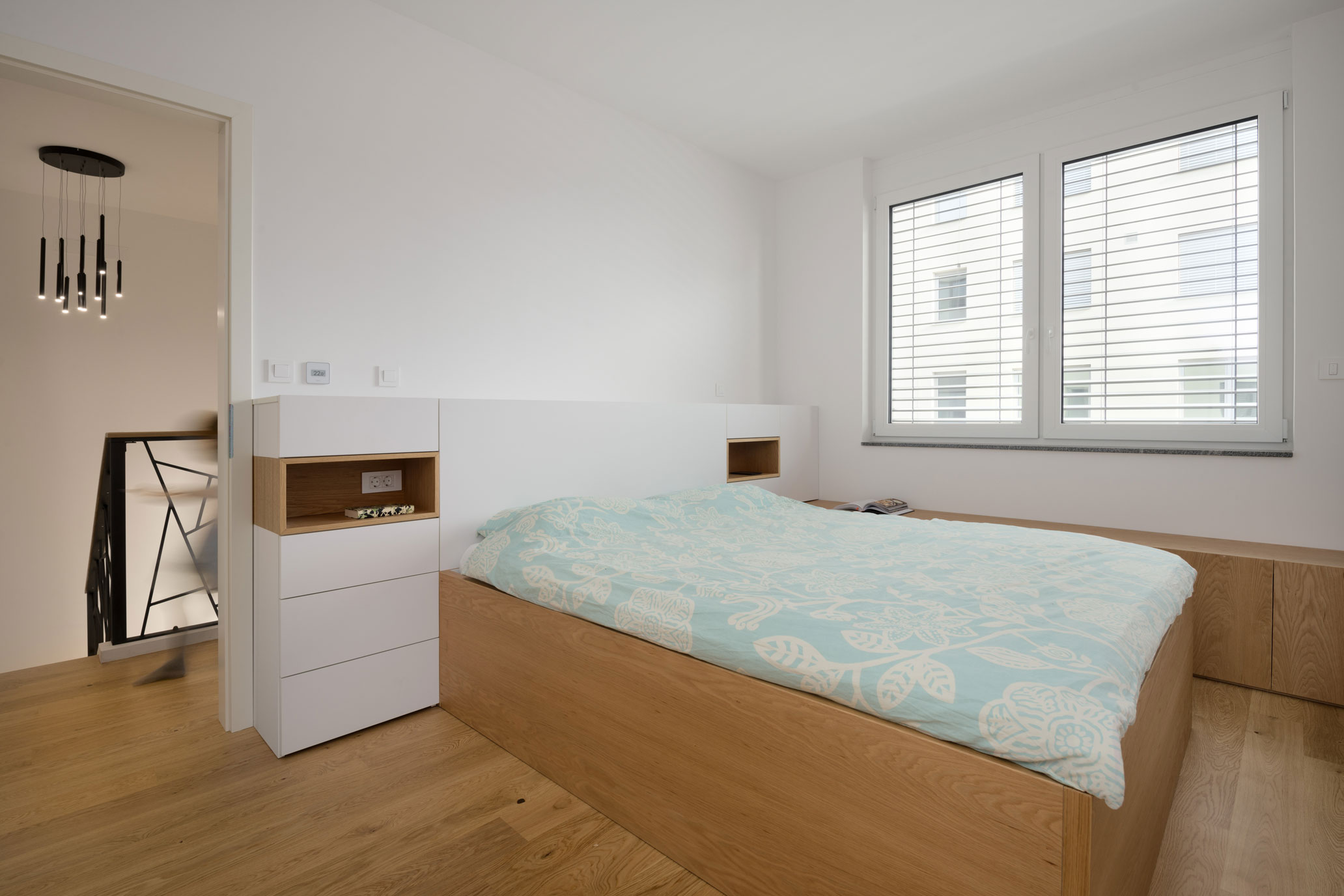 Svetla moderna spalnica s posteljo in nočno omarico z vgrajenimi vtičnicami