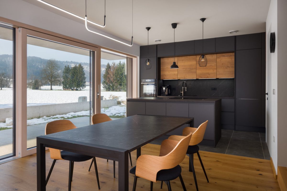Modern kitchen and dining room with black and wooden elements and access to the terrace