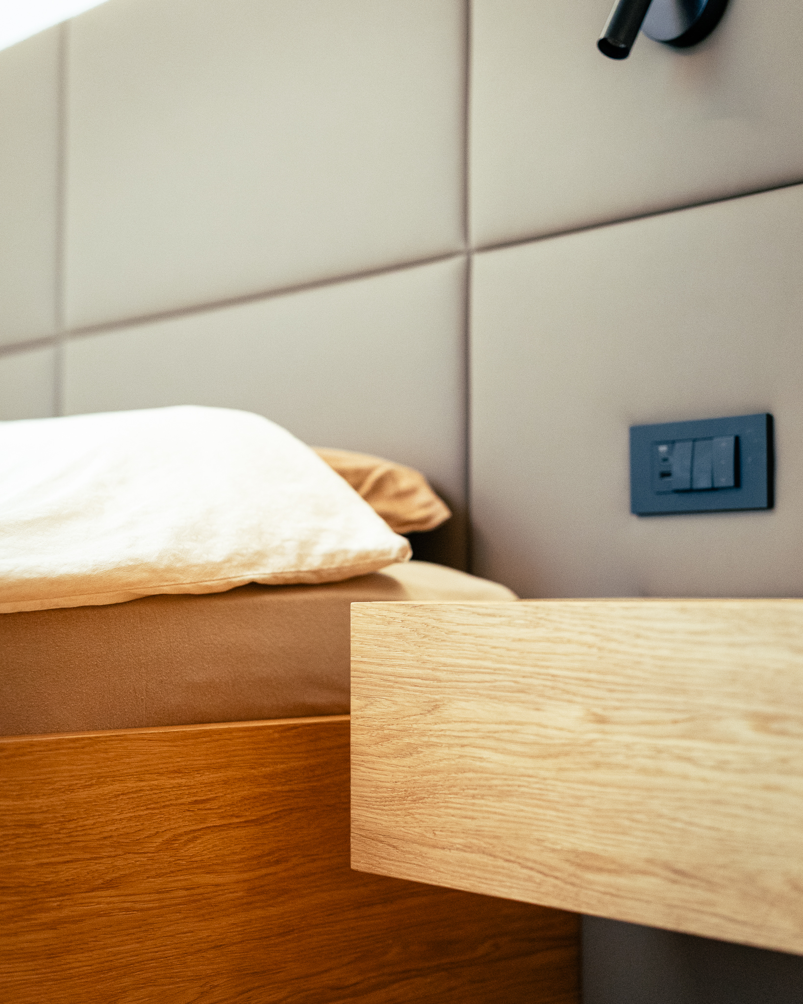 Detajl postelje in lesene nočne omarice ob njej