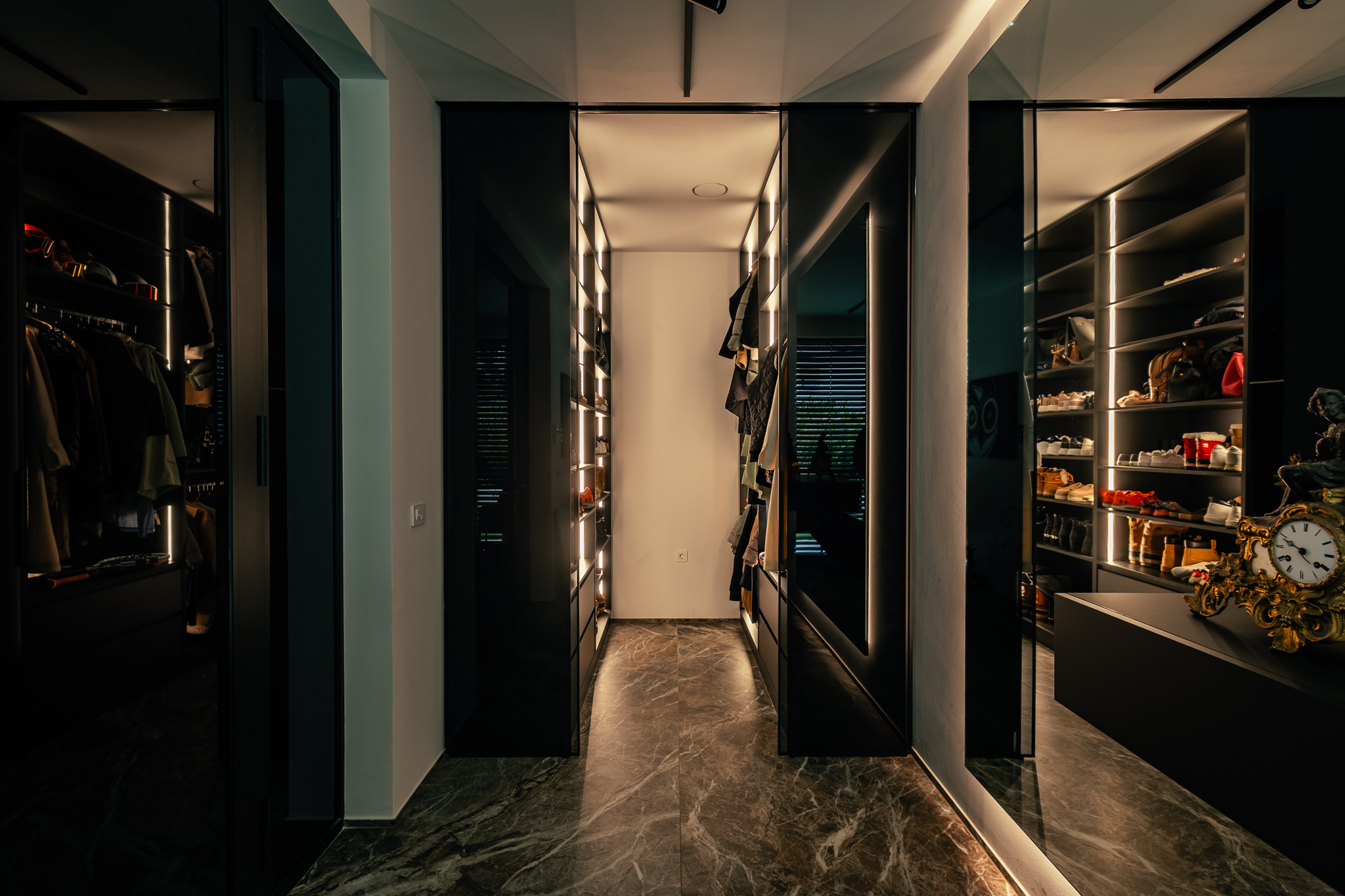 Prostorna, črna gardeobna soba z marmornatimi tlemi in osvetljavo