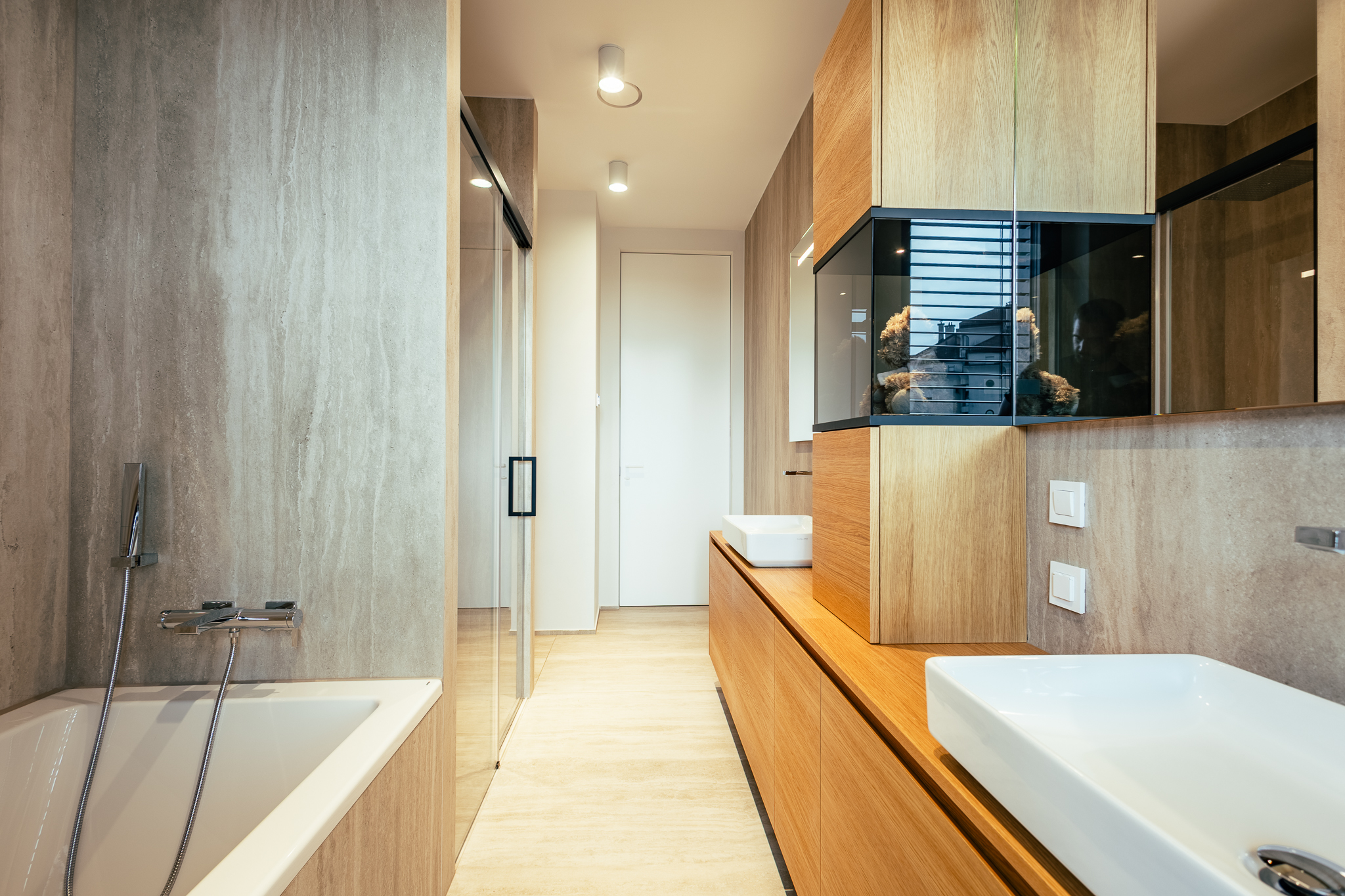 Otroška kopalnica z banjo, umivalnikom ogledali in sivo steno