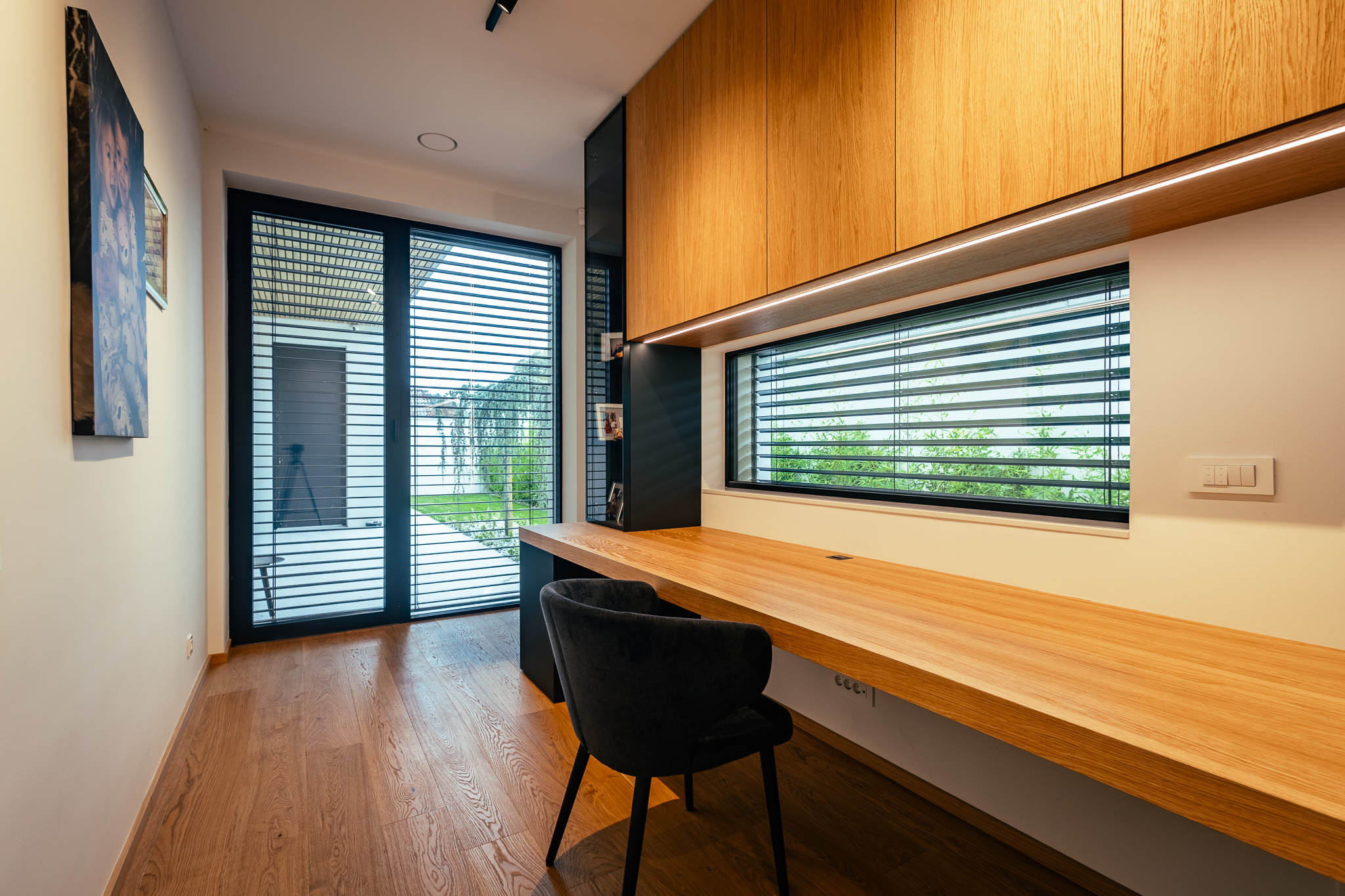 Domača pisarna z veliko leseno mizo in lesenimi omarami, ter izhodom na teraso