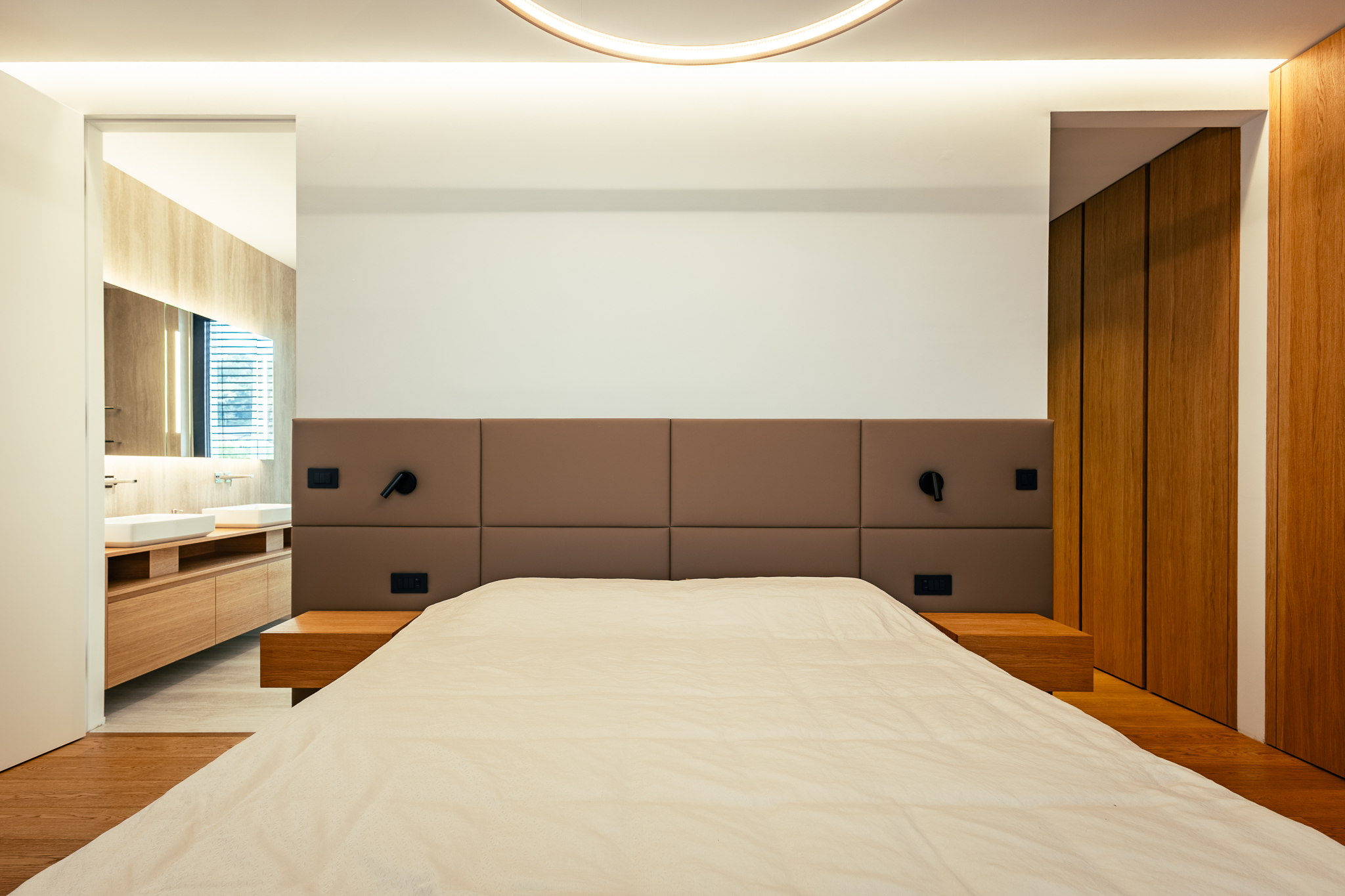 Postelja, ki ima leseno nočno polico na vsaki strani, v spalnici luskuzne vile