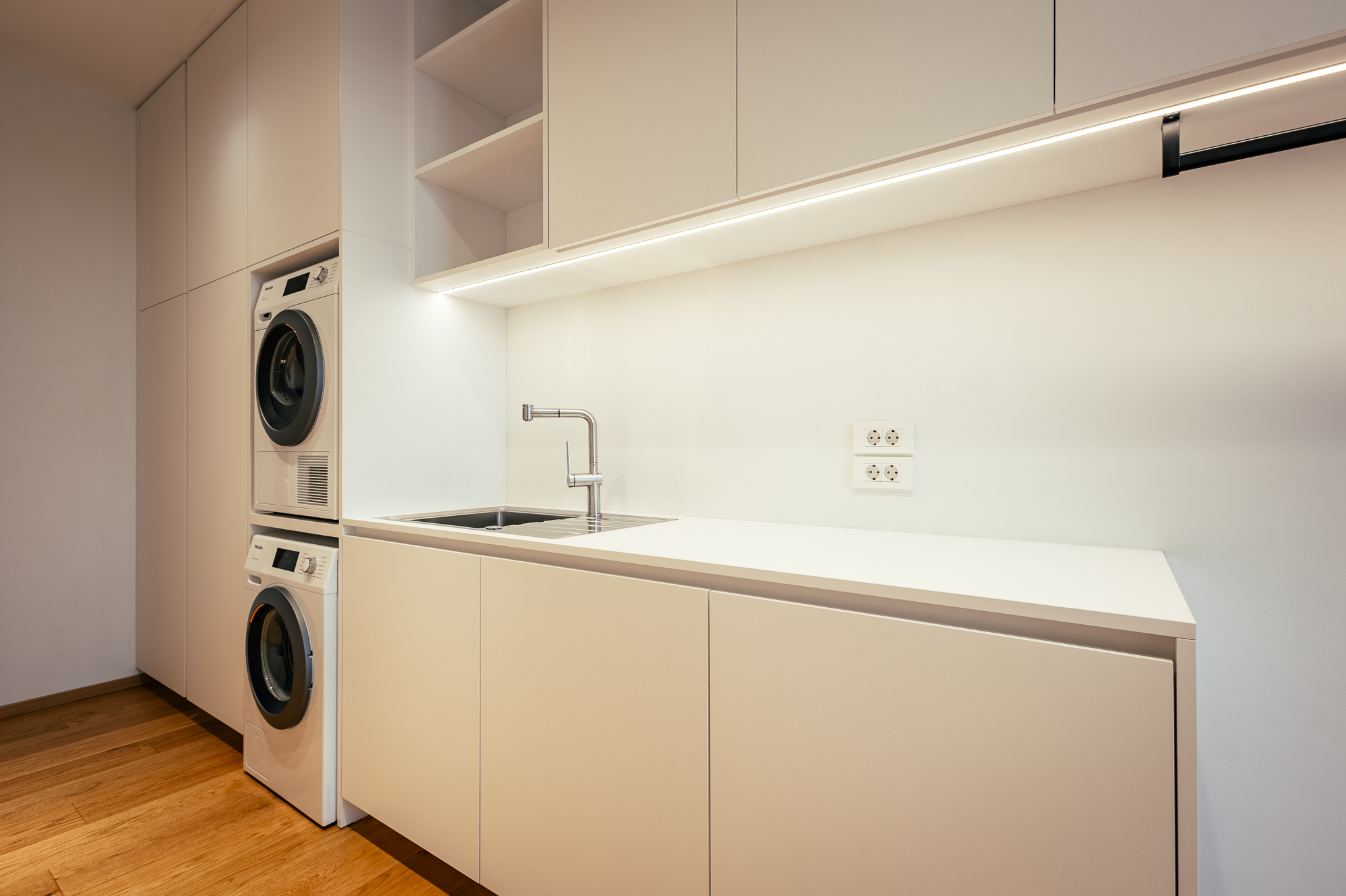 Bela soba z umivalnikom, pultom, pralnim strojem ter sušilcem