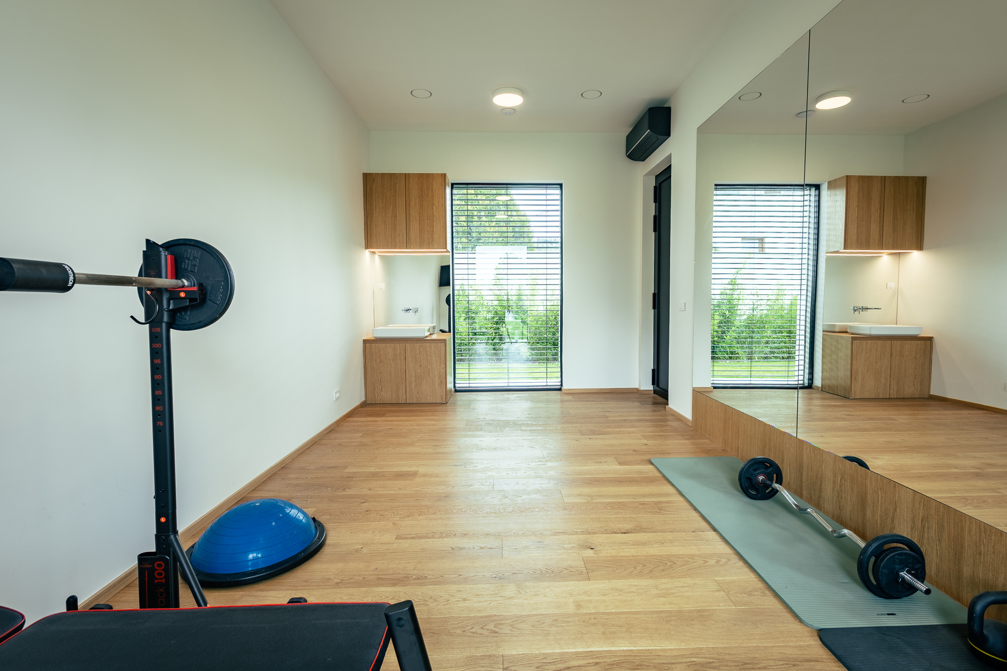 Vadbeni prostor z umivalnikom, velikim ogledalom, lesenim parketom, ter opremo za šport